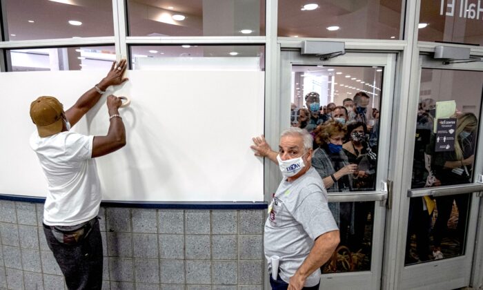 Des employés du bureau de vote cachent les fenêtres de l'aire de dépouillement des bulletins au centre TCF de Détroit, le 4 novembre 2020. (Seth Herald/AFP via Getty Images)