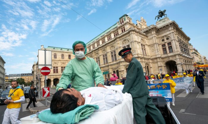 Des pratiquants de Falun Gong à Vienne, en Autriche, simulent une démonstration de prélèvements forcés d'organes sur des pratiquants emprisonnés en Chine lors d'une manifestation contre l'importation d'organes humains de Chine en Autriche le 1er octobre 2018. (Joe Klamar/AFP via Getty Images)