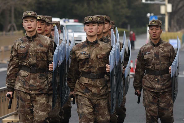 -Des soldats de l'Armée populaire de libération défilent vers leur caserne en face du Grand Hall du Peuple à Pékin le 24 février 2020. Photo by GREG BAKER/AFP via Getty Images. 