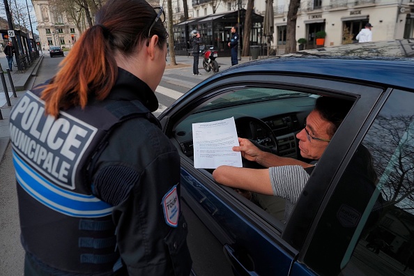 Une policière contrôle une attestation de déplacement. (GUILLAUME SOUVANT/AFP via Getty Images)