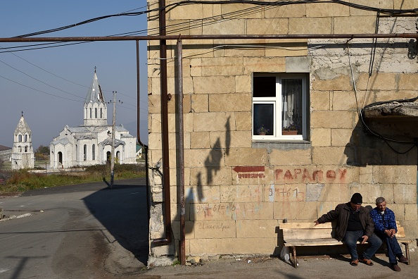 -Des hommes sont assis sur un banc devant un immeuble résidentiel non loin de la cathédrale endommagée dans la ville historique de Shusha, à environ 15 kilomètres de Stepanakert, le 1er novembre 2020. Photo de Karen Minasyan / AFP via Getty Images.