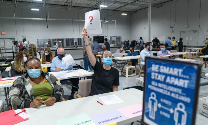 Une employée du comté de Gwinnett soulève un morceau de papier indiquant qu'elle a une question alors que le recomptage des bulletins commence à Lawrenceville, Géorgie, le 13 novembre 2020. (Megan Varner/Getty Images)