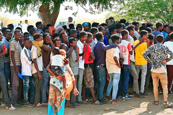 -Des réfugiés éthiopiens, qui ont fui des combats intenses dans leur pays d'origine, font la queue pour une portion de nourriture dans le camp d'Um Raquba, à l'est de Khartoum, le 15 novembre 2020. Photo par Ebrahim Hamid / AFP via Getty Images.