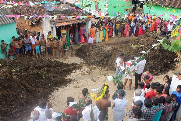 -Des gens se tiennent à côté de tas de bouse de vache pendant le festival "Gorehabba" au village de Gumatapura à la frontière des États du Karnataka et du Tamil Nadu en Inde, le 17 novembre 2020. Photo par Padmanabha Rao / AFP via Getty Images.