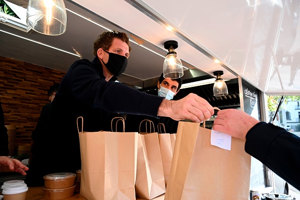 -Le chef français Alexandre Mazzia donne un panier-repas à un client alors que son équipe prépare des plats à emporter dans un food-truck à Marseille, dans le sud de la France, le 24 novembre 2020. Photo par Nicolas Tucat / AFP via Getty Images.