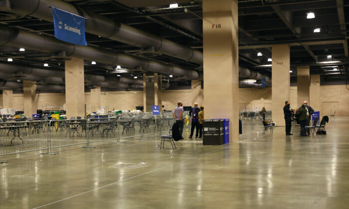 Des observateurs électoraux se tiennent derrière des barrières, loin de l'endroit où les bulletins de vote sont comptés, à l'intérieur de la salle de dépouillement du Centre de convention de Pennsylvanie à Philadelphie, en Pennsylvanie, le 6 novembre 2020. (Charlotte Cuthbertson/The Epoch Times)