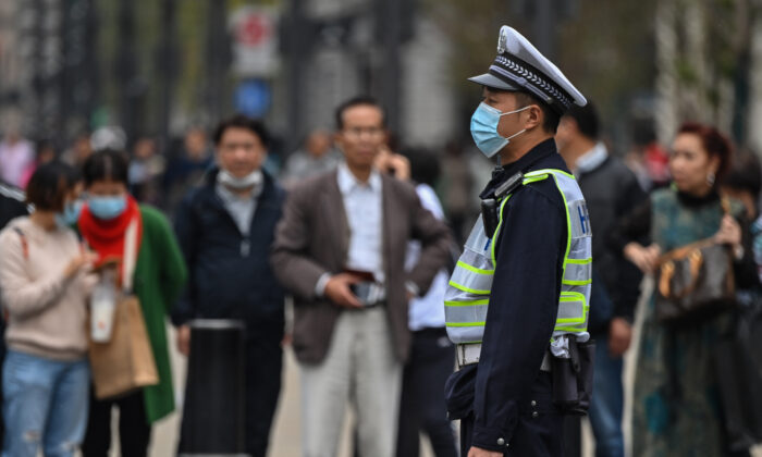 Un policier portant un masque facial surveille la circulation des piétons dans une rue de Shanghai le 28 octobre 2020. (Hector Retamal/AFP via Getty Images)