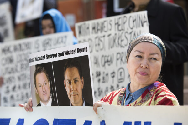 Turnisa Matsedik-Qira, de l'Association des Ouïghours de Vancouver, manifeste contre le traitement des Ouïghours par la Chine en tenant une photo des Canadiens détenus Michael Spavor et Michael Kovrig devant la Cour suprême de Colombie-Britannique, le 8 mai 2019, à l'occasion de la comparution de la directrice financière de Huawei, Meng Wanzhou. (Crédit photo Jason Redmond/AFP via Getty Images) 