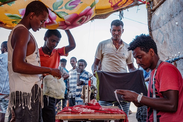 -Le tailleur réfugié éthiopien Omar Ibrahim travaille avec une machine à coudre louée dans un village soudanais voisin, le 9 décembre 2020. Photo par Yasuyoshi Chiba / AFP via Getty Images.