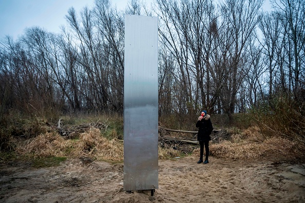 Une femme regarde un monolithe en métal qui a surgi sur une rive de la Vistule dans la capitale polonaise Varsovie. Des objets d'apparence similaire ont été trouvés aux États-Unis et en Europe. (Photo par Wojtek RADWANSKI / AFP) (Photo par WOJTEK RADWANSKI/AFP via Getty Images)