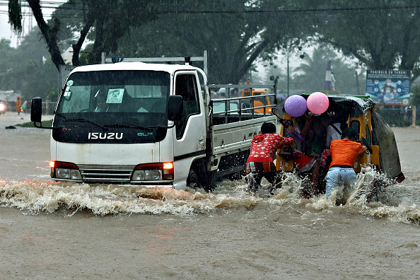 Des gens poussent un tricycle à moitié submergé dans une rue inondée en raison des fortes pluies sur l'île méridionale de Mindanao, le 18 décembre 2020. Photo par erwin mascarinas / AFP via Getty Images.