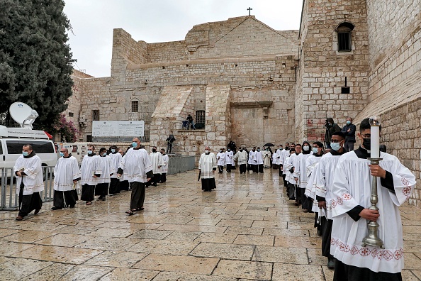 -Les diacres défilent avec des bougies lors d'une procession au début des célébrations de Noël à l'église de la Nativité dans la ville biblique de Bethléem en Cisjordanie le 24 décembre 2020. Photo par Jaafar Ashtiyed / AFP via Getty Images.