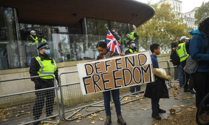 Un manifestant tient un panneau sur lequel est écrit « Défendre la liberté » lors d'une marche « Unis pour la liberté » devant le New Scotland Yard le 24 octobre 2020 à Londres. Des centaines de manifestants anti-masques et anti-confinement ont défilé dans le centre de Londres pour protester contre les dernières mesures de confinement face au coronavirus. (Photo par Peter Summers/Getty Images)