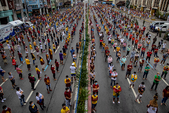 -Les fidèles observent la distanciation sociale alors qu'ils entendent la messe à l'extérieur de l'église de Quiapo pour célébrer la fête du Nazaréen noir le 9 janvier 2021 à Manille, Philippines. Photo par Ezra Acayan / Getty Images.