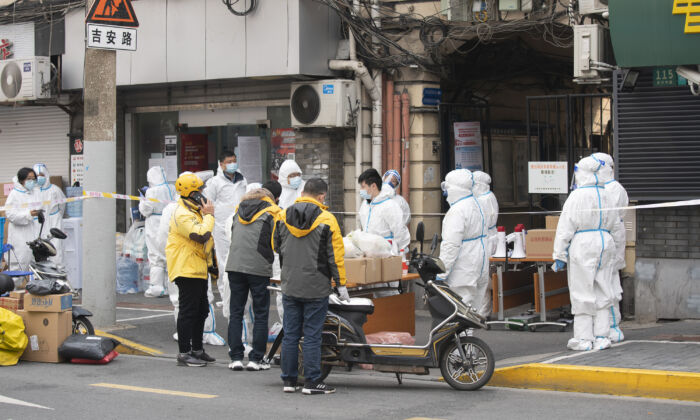 Des professionnels de la santé en combinaison de protection se trouvent dans le district de Huangpu à Shanghai, en Chine, le 28 janvier 2021. (Hu Chengwei/Getty Images)