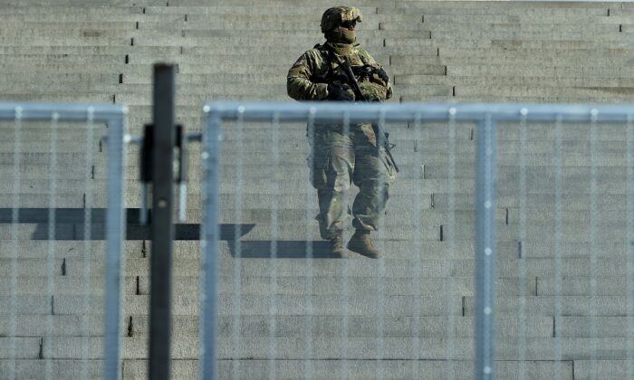 Un membre de la Garde nationale observe le cortège du président Joe Biden qui se rend au cimetière national d'Arlington pour une cérémonie de dépôt de couronnes au Tombeau des Inconnus après la 59e cérémonie d'inauguration présidentielle au Capitole, à Arlington, en Virginie, le 20 janvier 2021. (Chip Somodevilla/Getty Images)