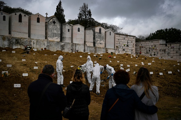 -Des fossoyeurs enterrent un cercueil au cimetière Alto de Sao Joao à Lisbonne le 18 février 2021. Photo Patricia De Melo Moreira / AFP via Getty Images.