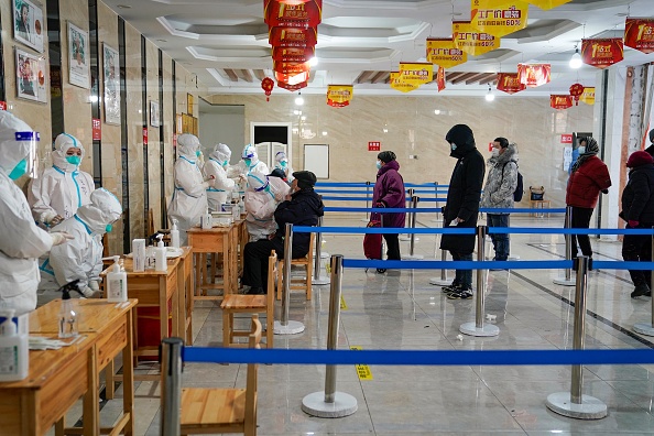 Un travailleur médical prélève un échantillon sur écouvillon sur un homme, dépistage de la Covid-19, nord-est de la Chine, le 14 janvier 2021. Photo par STR / AFP via Getty Images.