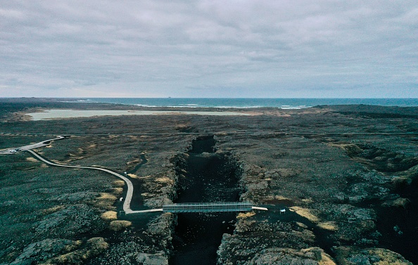 Une vue aérienne prise le 28 février 2021 montre le "Pont entre les continents", une passerelle reliant les plaques tectoniques eurasienne et nord-américaine, près de la ville de Grindavik sur la péninsule de Reykjanes, en Islande, à environ 50 kilomètres à l'ouest de la capitale Reykjavik, au sommet de la Mid-Atlantic Ridge, l'une des trois zones sismiques les plus actives de la planète. (Photo : HALLDOR KOLBEINS/AFP via Getty Images)