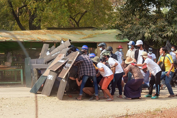 -Les manifestants s'abritent derrière des boucliers alors qu'ils affrontent les forces de sécurité lors d'une manifestation contre le coup d'État militaire, le 7 mars 2021, à Bagan. Photo de STR / AFP via Getty Images.