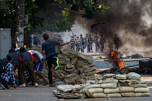 -Un manifestant lance un projectile sur les forces de sécurité alors que d'autres s'abritent derrière une barricade à Yangon le 17 mars 2021. Photo STR / AFP via Getty Images.