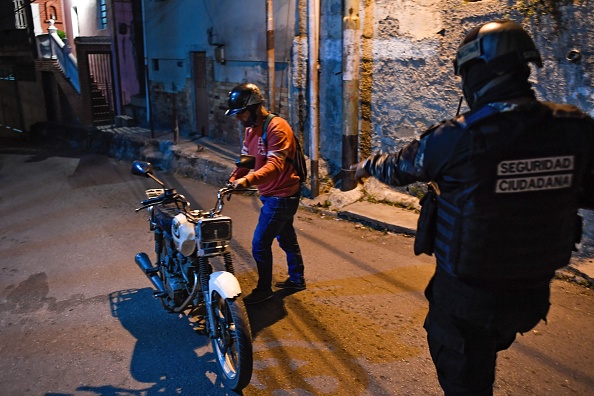 -Un membre de la police scientifique vénézuélienne se prépare à fouiller un homme, à Los Teques, État de Miranda, Venezuela, le 20 mars 2021. Photo par Federico Parra / AFP via Getty Images.