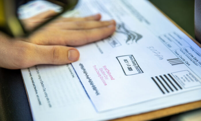 Un membre du personnel électoral tamponne le bulletin de vote d'un électeur avant de le déposer dans une urne sécurisée dans un lieu de dépôt des bulletins de vote, à Austin, au Texas, États-Unis, le 13 octobre 2020. (Sergio Flores/Getty Images)
