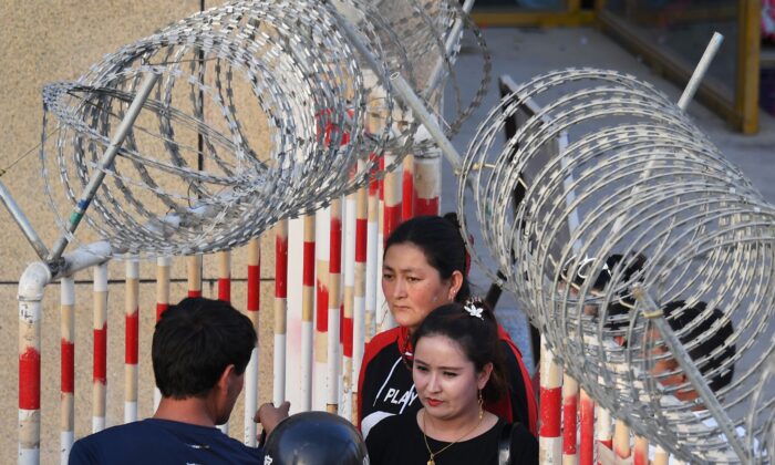 Une femme ouïghoure (au centre) pénètre dans un bazar à Hotan, dans la région du Xinjiang (nord-ouest de la Chine), le 31 mai 2019. (Greg Baker/AFP via Getty Images)