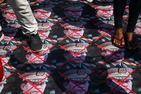 -Des manifestants marchent sur des portraits du chef des forces armées birmanes, le général Min Aung Hlaing, à Yangon le 5 mars 2021. Photo STR/AFP via Getty Images.