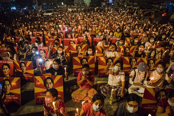 -Des manifestants portent des pancartes à l'effigie du dirigeant civil birman détenu Aung San Suu Kyi et organisent une veillée aux chandelles. Photo STR / AFP) via Getty Images.