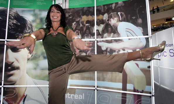 - La gymnastique roumaine Nadia Comaneci pose devant une photo d'elle aux Jeux Olympiques de 1976. Photo Saeed Khan / AFP via Getty Images.