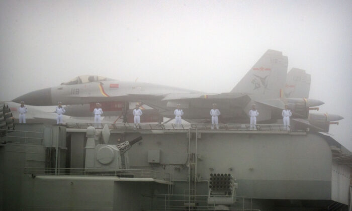 Des marins se tiennent près d'avions de chasse sur le pont du porte-avions Liaoning de la marine de l'Armée populaire de libération (APL), alors qu'il participe à un défilé naval pour commémorer le 70e anniversaire de la fondation de la marine de l'APL, en mer près de Qingdao, dans la province chinoise du Shandong (est), le 23 avril 2019. (Mark Schiefelbein/AFP via Getty Images)