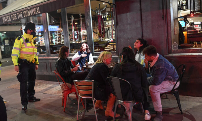 Un policier s'entretient avec des personnes assises devant un pub à Soho, à Londres, le 24 septembre 2020. (Peter Summers/Getty Images)