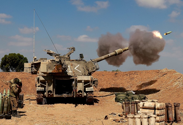 -Des soldats israéliens tirent d’un obusier vers la bande de Gaza depuis leur position, dans le sud d'Israël, le 13 mai 2021. Photo par Menahem KAHANA / AFP via Getty Images.