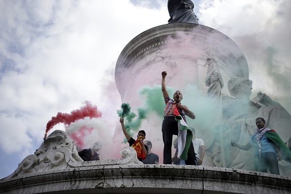 Des manifestants pro-palestiniens pulvérisent des fumigènes aux couleurs du drapeau palestinien, sur la place de la République à Paris, lors d'une manifestation interdite contre l'opération militaire d'Israël à Gaza et en soutien au peuple palestinien, le 26 juillet 2014. (Photo :  KENZO TRIBOUILLARD/AFP via Getty Images)