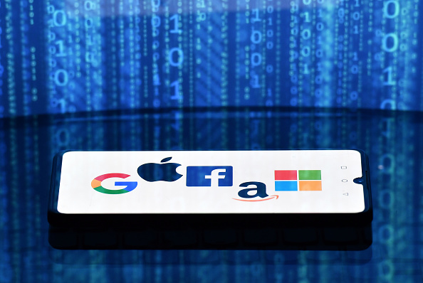 -Les logos de Google, Apple, Facebook, Amazon et Microsoft affichés sur un téléphone mobile et un écran d'ordinateur portable. Photo de JUSTIN TALLIS / AFP via Getty Images.