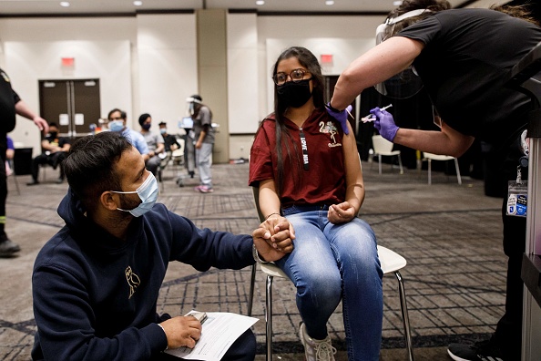 Une jeune femme tient la main de son compagnon pendant qu'elle se fait vacciner à Mississauga, Ontario. (COLE BURSTON/AFP via Getty Images)