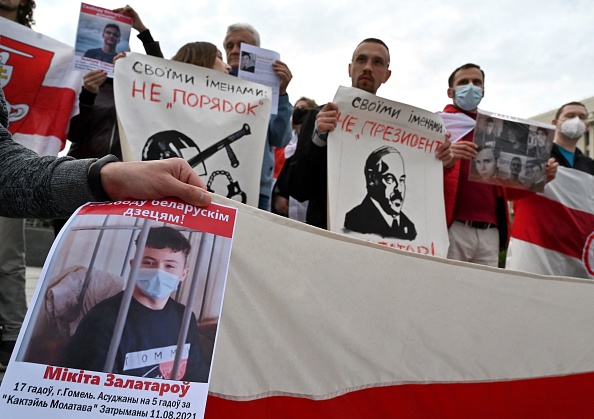 -Des membres de la diaspora biélorusse en Ukraine tiennent d'anciens drapeaux nationaux rouge et blanc de Biélorussie et des pancartes d'adolescents biélorusses emprisonnés lors des manifestations anti-Alexandre Loukachenko le 1er juin 2021. Photo de Sergei SUPINSKY / AFP via Getty Images.