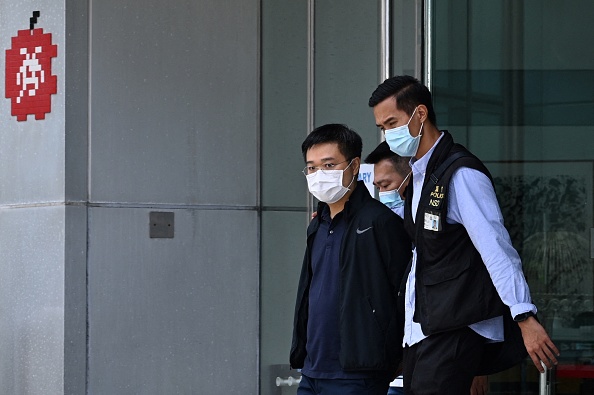 Le rédacteur en chef d'Apple Daily, Ryan Law, est escorté par la police jusqu'à un véhicule en attente à Hong Kong le 17 juin 2021. (Photo par Anthony WALLACE / AFP via Getty Images.)