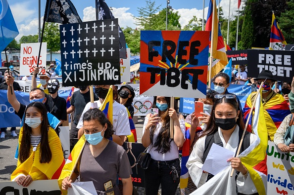 Des activistes tibétains et ouïghours brandissent des pancartes lors d'une manifestation contre les Jeux olympiques d'hiver de Pékin 2022 devant le Musée olympique à Lausanne, le 23 juin 2021. (Photo : FABRICE COFFRINI/AFP via Getty Images)