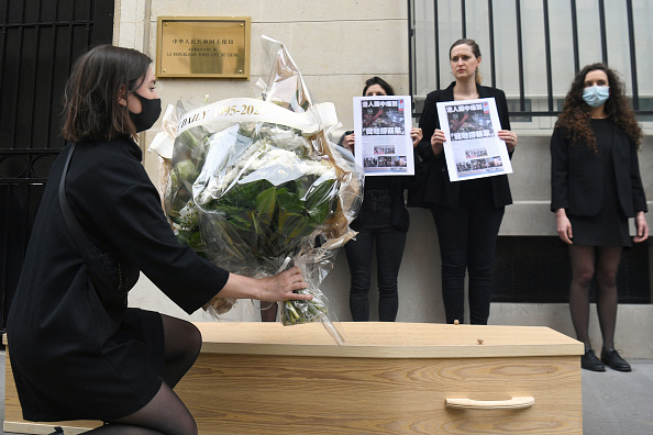 -Un manifestant dépose des fleurs au sol à l'ambassade de Chine à Paris, le 25 juin 2021, en soutien au quotidien Apple Daily, qui a été contraint de fermer en vertu de la nouvelle loi sur la sécurité nationale de Hong Kong. Photo par Alain JOCARD / AFP via Getty Images.