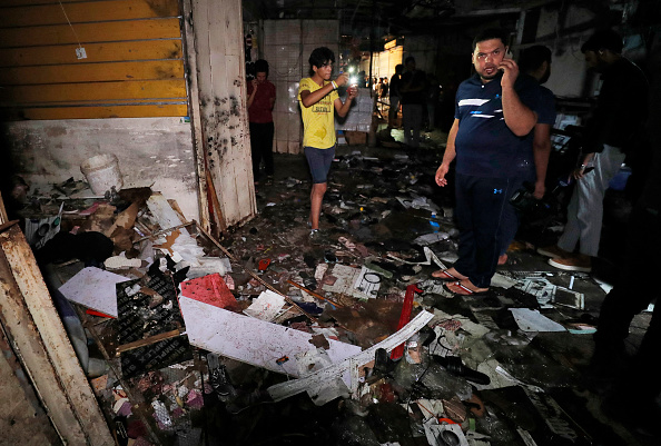 -Des Irakiens inspectent le site de l'explosion dans un marché populaire du quartier majoritairement chiite de Sadr City, à l'est de Bagdad, le 19 juillet 2021. Photo AHMAD AL-RUBAYE/AFP via Getty Images.