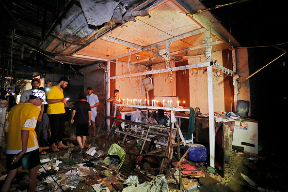 Des Irakiens allument des bougies sur le site de l'explosion dans un marché populaire du quartier majoritairement chiite de Sadr City, à l'est de Bagdad, le 19 juillet 2021.