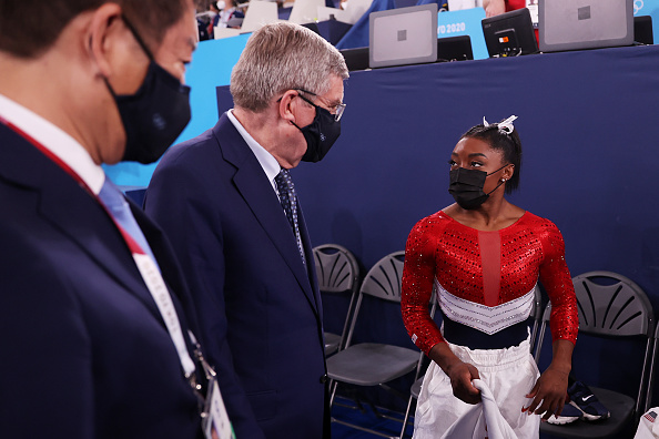 -Le président du Comité international olympique Thomas Bach s'entretient avec Simone Biles de l'équipe des États-Unis lors de la finale par équipe féminine le quatrième jour des Jeux Olympiques de Tokyo 2020 le 27 juillet 2021, Japon. Photo de Laurence Griffiths/Getty Images.