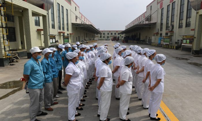 Des travailleurs sont alignés pour chanter des chants communistes « rouges » dans une usine de nouilles instantanées dans la province chinoise du Henan, le 29 septembre 2017. Récemment, le Parti communiste chinois a étendu davantage son contrôle sur les entreprises, tant privées qu'étrangères, par le biais des organisations du Parti qui y sont installées. (Greg Baker/AFP/Getty Images)