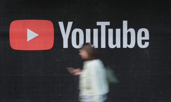 Une femme avec un smartphone passe devant un panneau publicitaire de YouTube à Berlin, le 27 septembre 2019. (Sean Gallup/Getty Images)