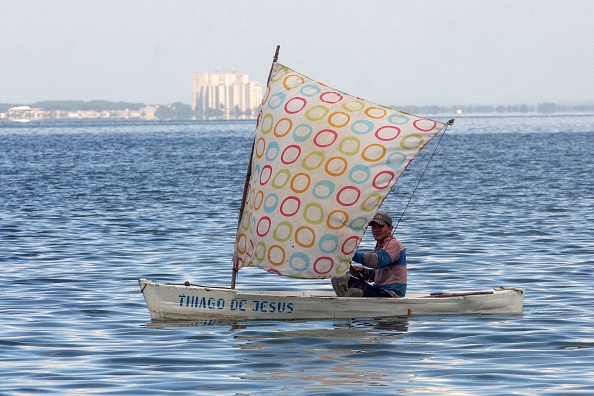 -Un homme pêche dans les eaux polluées du lac Maracaibo, Venezuela, le 30 juillet 2021. Photo de LUIS BRAVO / AFP via Getty Images.