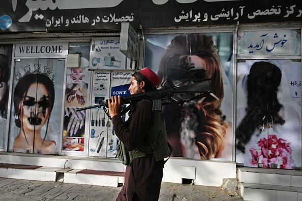 - Un combattant taliban passe devant un salon de beauté avec des images de femmes défigurées à l'aide de peinture en aérosol à Kaboul le 18 août 2021. Photo Wakil KOHSAR / AFP via Getty Images.