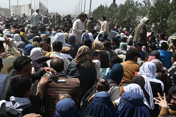 -Des Afghans se rassemblent au bord d'une route près de la partie militaire de l'aéroport de Kaboul le 20 août 2021, dans l'espoir de fuir le pays. Photo Wakil KOHSAR / AFP via Getty Images.