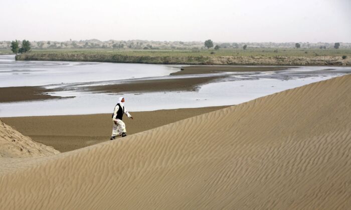 Un citoyen de Keriyan marche sur les dunes de sable le long de la rivière Keriyan dans le village de Daheyan du comté de Yutian de la région du Xinjiang, en Chine, le 10 septembre 2007. (China Photos/Getty Images)